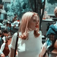 a woman with red lipstick standing in front of a group of people on a city street