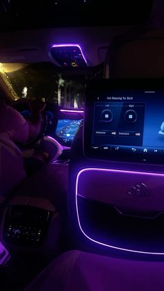 the interior of a car with purple lights and electronic gadgets on it's dashboard