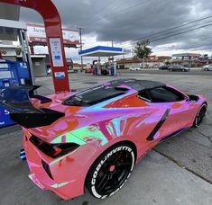 a pink sports car parked in front of a gas station