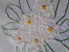 a close up of a white and green flower on a piece of cloth with stitching