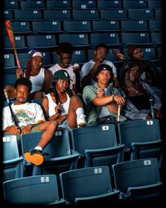 a group of people sitting in the bleachers at a baseball game with bats