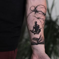 a person with a book tattoo on their arm holding an open book in the air