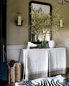 a white table topped with a vase filled with flowers and a zebra print rug next to it