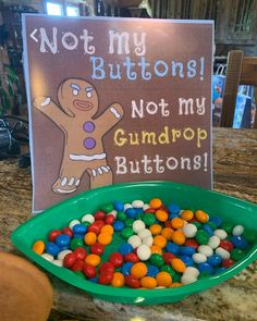 a green bowl filled with candy next to a sign that says not my buttons not my gumdrop buttons