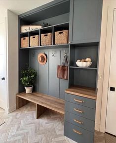 a room that has some shelves and drawers on the wall, with baskets in front of it