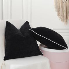 a black pillow sitting on top of a white chair