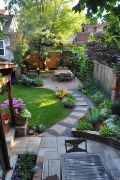 a small backyard with a table and chairs in the center, surrounded by flowers and trees