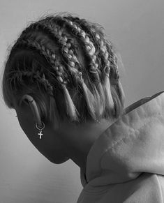 a woman with braids in her hair looking down at the ground while wearing an earring