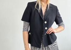 "Vintage single breasted black jacket blazer for women. Lining, short sleeves, button closure, two front pockets, white pearl shell buttons. Brand: Andiata Material: 65% viscose, 35% virgin wool Great vintage condition. Please check measurements to insure a proper fit.  (You can compare this with something from your closet that fits you well.) Measured laying flat: 23\" / 58.5 cm long 19\" / 48.5 cm armpit to armpit 16\" / 40.5 cm shoulders seam to seam If you have any questions, please let me k Classic Short Sleeve Blazer With Buttons, Short Sleeve Blazer With Button Closure For Work, Office Short Sleeve Blazer With Button Closure, Classic Fitted Short Sleeve Blazer, Fitted Short Sleeve Blazer With Buttons, Elegant Short Sleeve Blazer With Buttons, Fitted Short Sleeve Blazer With Button Closure, Vintage Single Button Spring Blazer, Vintage Single-breasted Button-up Blazer