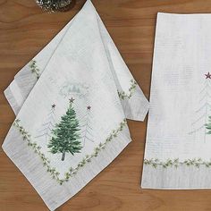 three christmas tree napkins on top of a wooden table