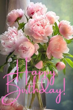 a vase filled with pink peonies on top of a table next to a window