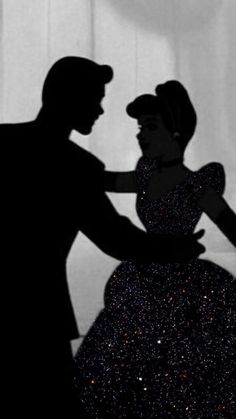 a man and woman are dancing together in the dark, silhouetted against a curtain