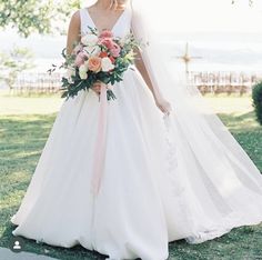 a woman in a wedding dress holding a bouquet and posing for the camera with her hand on her hip