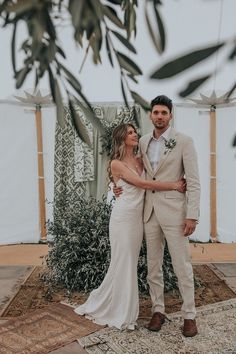 a man and woman standing next to each other in front of a white canvas tent