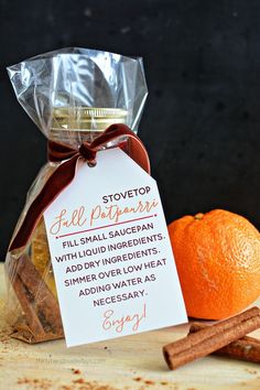 an orange sitting next to some cinnamon sticks and a bag with a note on it