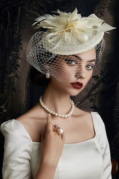 a woman wearing a white dress and veil with a flower on her head is posing for the camera