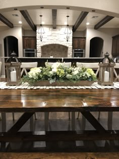 a table with flowers and candles on it in a large open kitchen area next to a fireplace