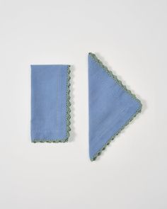 two pieces of cloth with scalloped edges on a white surface, one blue and the other green