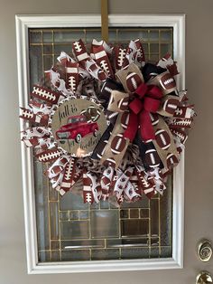 a football wreath is hung on the front door with a red and white bow attached to it