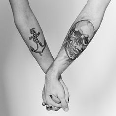 two people holding hands with tattoos on their arms