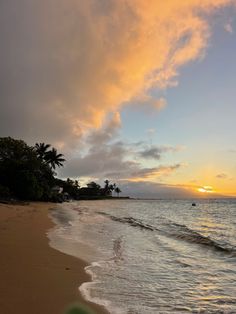 the sun is setting over the ocean with waves coming in to shore and palm trees lining the shoreline