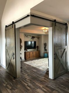 an open barn door leading to a living room with a flat screen tv on the wall