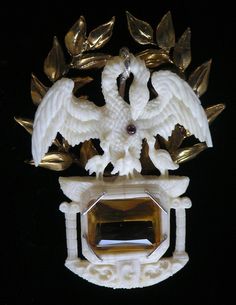 an ornate white and gold brooch with two birds on it's center piece