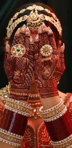 a woman with her hands covered in hendi and jewelry, showing the intricate designs on her hands