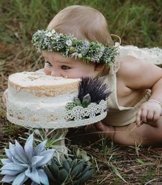 a baby in a dress is holding a cake with succulents on it