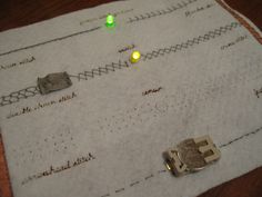 a close up of a piece of paper on a table with some buttons and wires attached to it