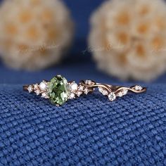 a ring with an oval green stone surrounded by small white diamonds on a blue cloth