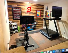 a home gym with treadmills, exercise bikes and monitors on the wall behind it