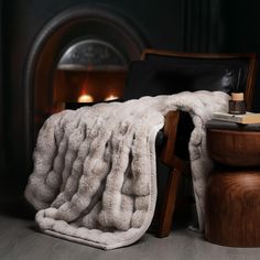 a chair with a blanket on it next to a fire place