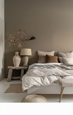 a bed with white linens and pillows in a neutral colored room, next to two lamps