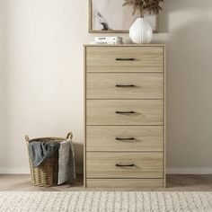 a white vase sitting on top of a wooden dresser next to a basket and rug