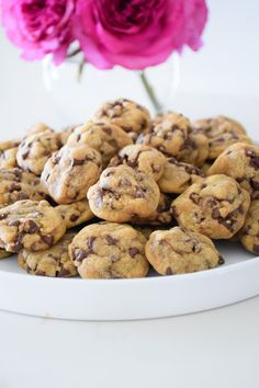 chocolate chip cookies on a white plate with pink flowers in the backgrouf