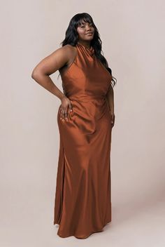 a woman in an orange dress poses for the camera with her hands on her hips