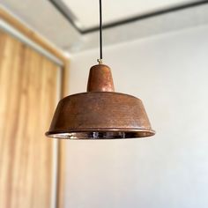 a metal light hanging from a ceiling in a room with wood paneling and white walls