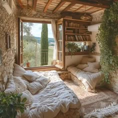 a bed sitting under a window in a bedroom next to a book shelf filled with books