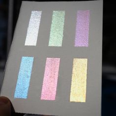 a person holding up a piece of paper with different colored strips on it and the other half