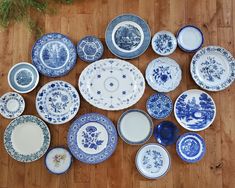 a collection of blue and white plates sitting on top of a wooden floor