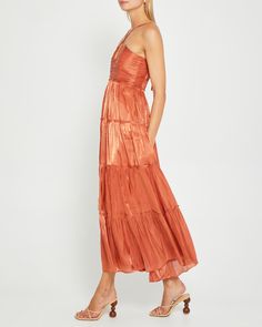 a woman is wearing an orange dress with tiered ruffles on the bottom