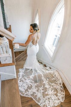 a woman in a wedding dress is standing on the stairs and looking at her reflection