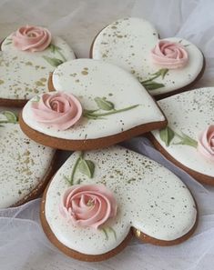 several decorated cookies with pink roses on them are arranged in a heart shape and placed next to each other