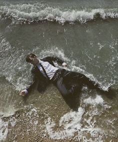 a man in a suit laying on the beach