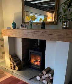 a fire place with logs in front of it and a mirror on the wall above