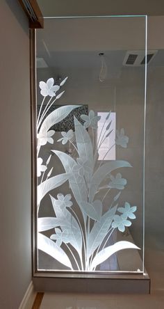 a glass shower door with flowers etched on it