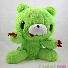 a green teddy bear sitting on top of a white surface with its mouth open and tongue out