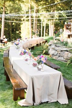 a long table with flowers on it is set up in the middle of a grassy area