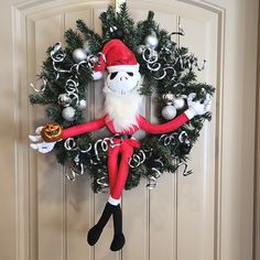 a christmas wreath hanging on the front door with an elf figure and decorations around it